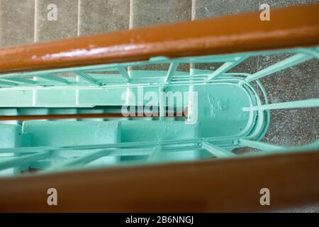 Treppenblick von oben. Treppenaufgang im Treppenhaus nach der Reparatur. Braunes Geländer, grüne Farbe. Stockfoto