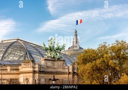 Eine von zwei Quadrigaskulpturen und eine französische Flagge, die im Museumsgebäude Grand Palais in Paris, Frankreich, aufgestellt wurde Stockfoto