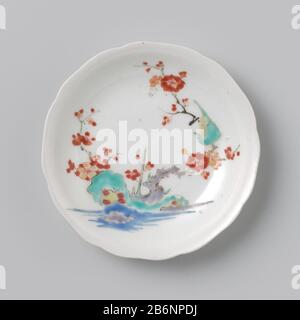 Gelobde schotel traf auf Bloemtak en vogel Gelobde schotel van porselein, beschilderd op het glazuur in blauw, Rood, Groen, geel, aubergine en zwart, met op de kop een vogel met chrysantakken, op de schotel een vogel in een prunustak bij rotsen Wasser. Bakscheur im Voetring. KOP hoort Stockfoto