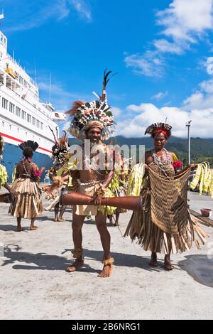 dh Port PNG heimisch willkommen AALTAU PAPUA NEUGUINEA traditionelles Kleid Willkommen Kreuzfahrtschiffbesucher Menschen Tourismus Tribal Drum Stockfoto