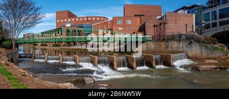 Ein Panoramablick auf eine Fußgängerbrücke und einen Staudamm am Reedy River im Stadtzentrum von Greenville, South Carolina Stockfoto