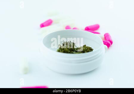 Eine weiße medizinische Schachtel Cannabis und eine weiße Schachtel bunter Pillen. Konzept der medizinischen Cannabistherapie Stockfoto