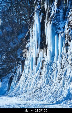 Große Eiszapfen hängen von River Bank Cliff. Stockfoto