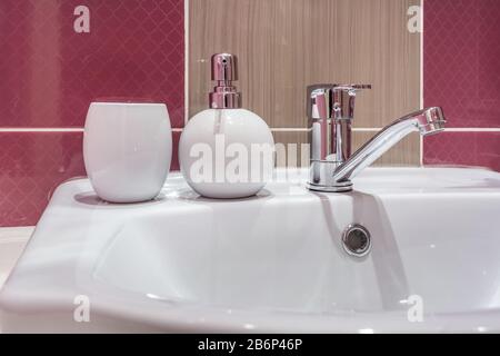 Seife und Shampoo-Dispenser in der Nähe Von Keramischen Wasserhahn-Spüle mit Hahn im teuren Loft-Bad oder in der Küche Stockfoto