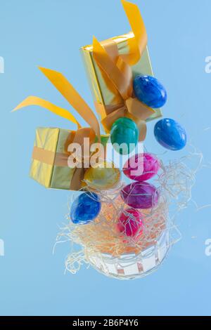 Holzkorb mit schwebenden Geschenkschachteln und ostereiern Stockfoto