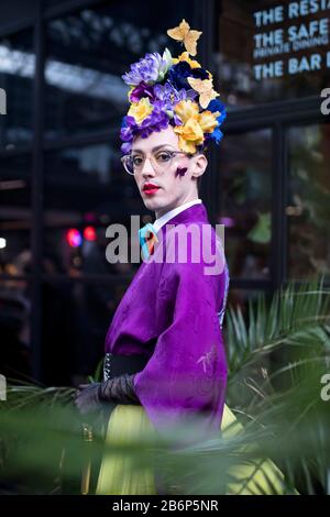 London, Großbritannien - febryary 15 2020: Modische Menschen auf der Straße . Straßenstil. Ein Mann in einem violetten Kimono mit einem hellen Make-up und einer Krone aus Eimell Stockfoto