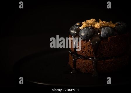 Schokoladenmuffins mit Blaubeeren auf schwarzem Hintergrund, Moody Style, Food-Foto mit dunklen Farben, Vorderansicht, Nahaufnahme Stockfoto
