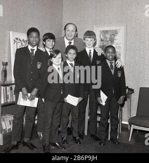 1972 posierte der historische, Legendäre britische Schwergewichtsboxer Henry Cooper für ein Bild mit einer Gruppe von Schuljungen bei einem Besuch einer Innenstadt-Realschule in Catford, Süd-Ost London, England, Großbritannien. Stockfoto