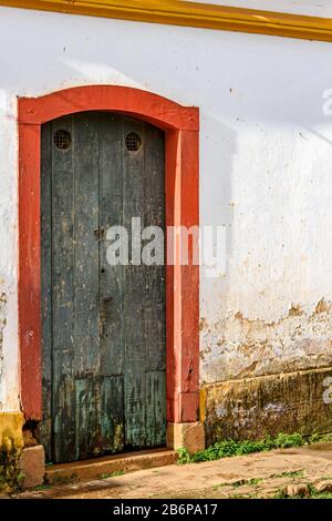 Alte Holztür in einem Haus mit kolonialer Architektur, das von Zeit zu Zeit in der Stadt Tiradentes, Bundesstaat Minas Gerais, getragen wurde Stockfoto