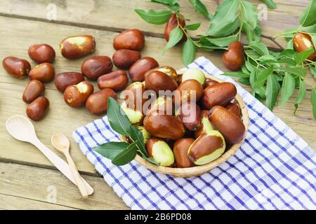 Korbkorb mit Früchten Ziziphus Real, Capiente, Jujube, chinesisches Datum, Capiinit, Jojoba, China-Datum (lat.Ziziphus jujujuba) und Holzlöffel auf dem Stockfoto