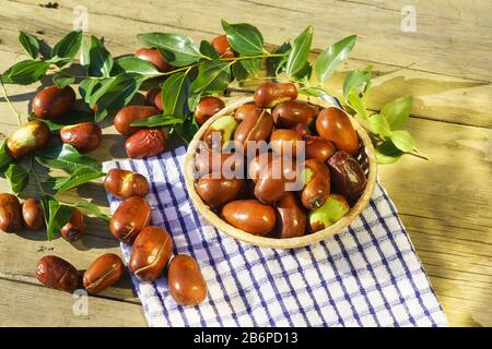 Korbkorb mit Ziziphus echten Früchten, Kopfsteinpflaster, Unabi, Capiente, Marmalade, Capiinit, Jojoba, chinesisches Datum im Sonnenlicht auf dem Tisch. Herbststil Stockfoto