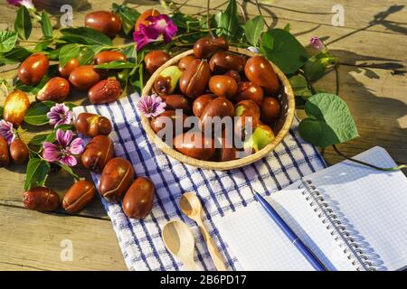 Korbkorb mit Ziziphus echten Früchten, Kopfsteinpflaster, Unabi, Capiente, Marmalade, Capiinit, Jojoba, chinesische Datteln an blauer Serviette im Sonnenlicht. Herbst Stockfoto