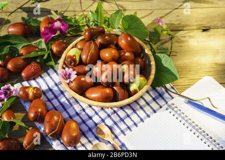 Korbkorb mit Ziziphus echten Früchten, Kopfsteinpflaster, Unabi, Capiente, Marmalade, Capiinit, Jojoba, chinesisches Datum und Notepad für Aufzeichnungen in den Strahlen o Stockfoto