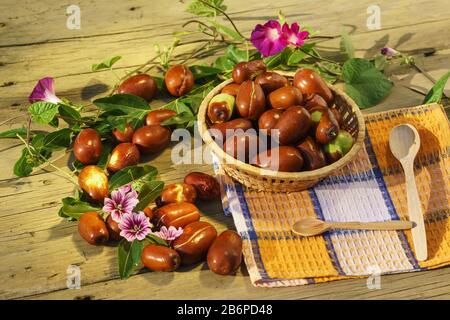 Korbkörbchen mit reifen Früchten von Ziziphus Real, Kobblestein, Unabi, Capiente, Marmalade, Capiinit, Jojoba, Chinesisch datieren mit Maulblumen auf einem Yell Stockfoto