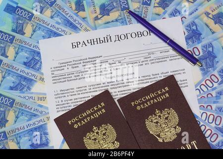 Vor dem Hintergrund des russischen Papiergeldes handelt es sich um eine Form von Heiratsvertrag, ein Stift und zwei Pässe. Die Aufschrift im russischen Ehekontrakt Co Stockfoto