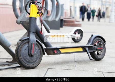 Elektrische Roller hintereinander auf dem Parkplatz. Stadtradverleih, öffentliche E-Roller auf der Straße Stockfoto