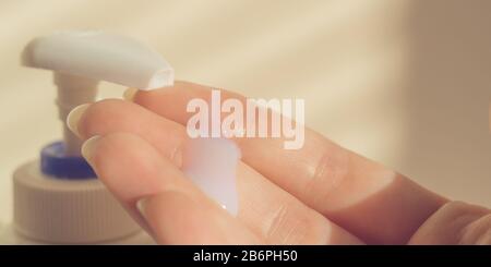 Eine weibliche Hand verwendet flüssige Seife mit Spender. Weißes Gel an den menschlichen Fingern. Stockfoto