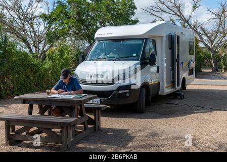 Tourist Reisen mit Wohnmobil Studium Karte auf seinem privaten Platz im Hauptcamp im Addo Elephant National Park, Südafrika Stockfoto