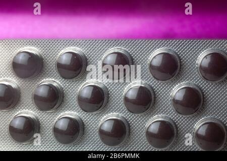 Studio mit braunen Pillen in Blister auf violettem Hintergrund Stockfoto