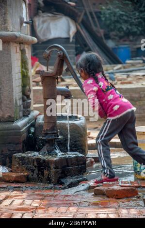 Kleines Mädchen, das Wasser von der Pumpe erhält Stockfoto
