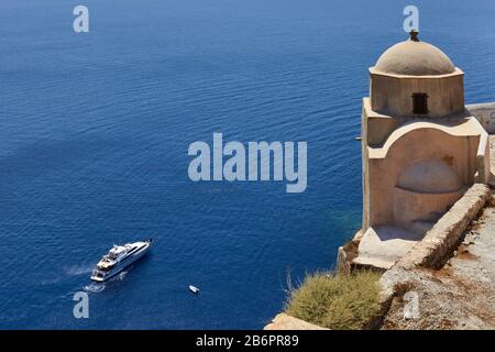 Oia, Santorini, Griechenland, 21. August 2013: Blick auf eine kleine Kirche und eine Luxusyacht, die im blauen Meer segelt Stockfoto