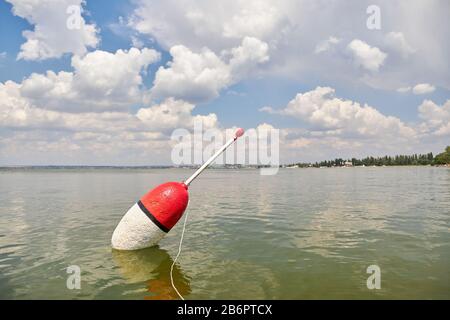 Auf der ruhigen Oberfläche des Sees schwebt ein großer Schwimmer, der auf den Biss wartet. Stockfoto