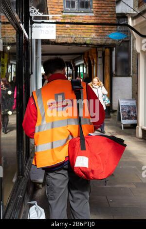 Ein Postbote von Royal, der Post auf der Straße mit einem Postsack auf der Schulter liefert Stockfoto