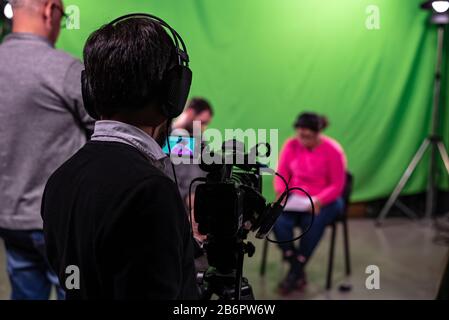 Produzent spricht mit dem Interviewten und Kameramann und überprüft den Fokus auf den Journalisten Stockfoto