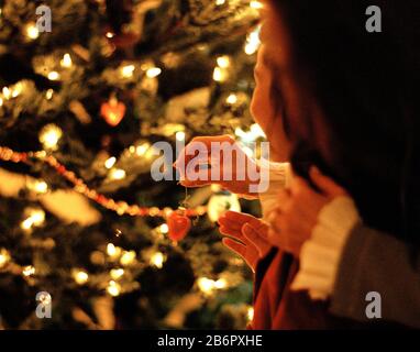 Mutter und Tochter hängen Dekorationen an einem Weihnachtsbaum Stockfoto