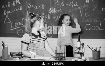 Bildungsexperiment. Mädchen Klassenkameraden studieren Chemie. Mikroskopteströhrchen chemische Reaktionen. Schüler im Chemieunterricht am Schwarzen Brett. Laborpraxis. Chemieklassen. Faszinierende Wissenschaft. Stockfoto