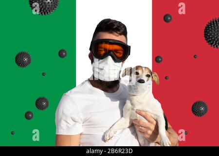 Mann in Schutzmaske und Brille mit Hund mit Gesichtsmaske und abstrakter Virusbelastung auf italienischem Flaggenhintergrund. Konzept der Prävention von Coronavirus-Kovid-19-Pandemie Stockfoto