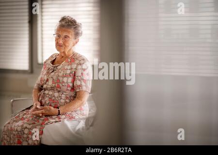 Portrait eine alte Frau sitzt auf einem Bett. Stockfoto