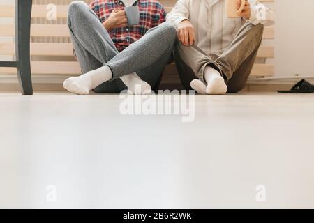 Ein Porträt von Erwachsenen hipster Sohn und Vater auf dem Boden drinnen, zu Hause zu sitzen. Stockfoto