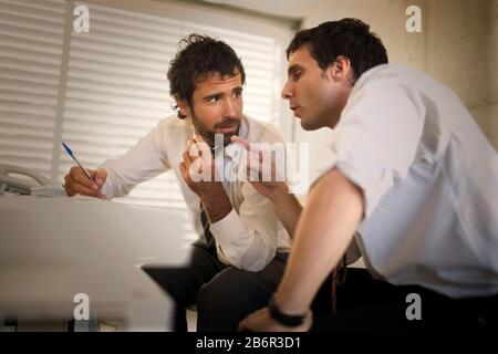 Zwei Geschäftsleute in einer Diskussion an einen Schreibtisch in einem Büro. Stockfoto