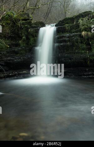Der Wasserfall A und der Fluss im Morgennebel in der Campsie Glan Schlucht im Westen Schottlands. Stockfoto