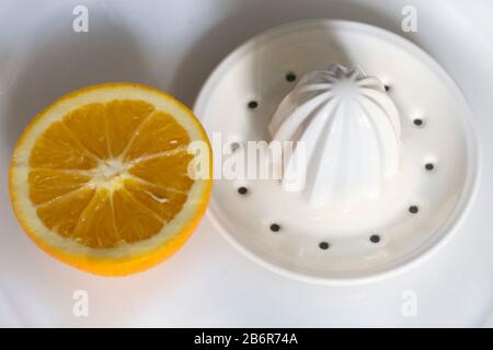 Eine orangefarbene und weiße Zitruspresse aus Keramik auf einem Teller. Stockfoto