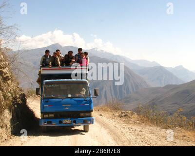 Celendin, Cajamarca, Peru. Eine Gruppe von Menschen, die auf einem LKW sitzen und über eine Straße fahren, um sie zu transportieren. Andengebirge im Hintergrund Stockfoto