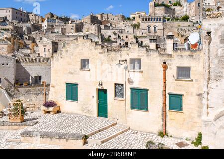 Blick auf eine Wohngegend mit einem Haus mit grünen Türen in der alten Höhlenstadt Matera, Italien, einer UNESCO-Welterbestätte. Stockfoto