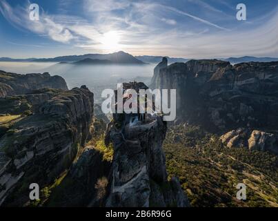 Luftbild der Trinität des Klosters und atemberaubende Bilder des Tals und des Wahrzeichen Canyons von Meteora bei Sonnenuntergang, Kalambaka, Griechenland, Schatten, verdrehte roa Stockfoto