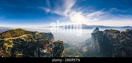 Luftbild der Trinität des Klosters und atemberaubende Bilder des Tals und des Wahrzeichen Canyons von Meteora bei Sonnenuntergang, Kalambaka, Griechenland, Schatten, verdrehte roa Stockfoto