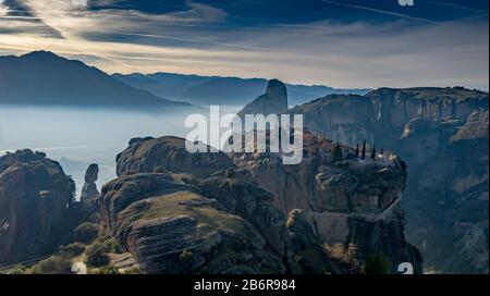 Luftbild der Trinität des Klosters und atemberaubende Bilder des Tals und des Wahrzeichen Canyons von Meteora bei Sonnenuntergang, Kalambaka, Griechenland, Schatten, verdrehte roa Stockfoto