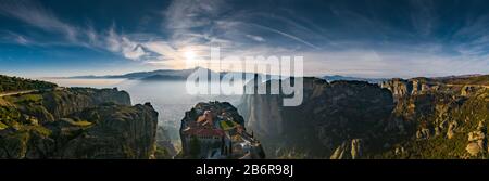 Luftbild der Trinität des Klosters und atemberaubende Bilder des Tals und des Wahrzeichen Canyons von Meteora bei Sonnenuntergang, Kalambaka, Griechenland, Schatten, verdrehte roa Stockfoto