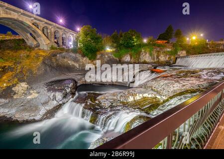 Am späten Abend wurden die Spokane Falls and Bridge im Bereich des Riverfront Park in Spokane, Washington, USA, mit einem langen Belichtungsschuss aufgenommen. Stockfoto