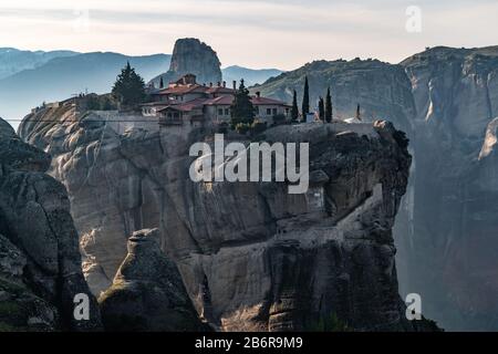 Luftbild der Trinität des Klosters und atemberaubende Bilder des Tals und des Wahrzeichen Canyons von Meteora bei Sonnenuntergang, Kalambaka, Griechenland, Schatten, verdrehte roa Stockfoto