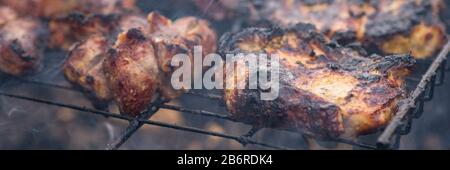 Geröstetes Schweinefleisch beim Grill. Seitenansicht, Nahaufnahme. Stockfoto