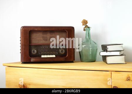 Vintage-Radio aus Holz, grüner Vase und alten Büchern auf einem Tisch Stockfoto