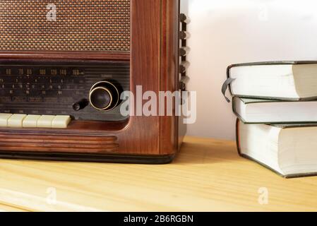 Vintage-Radio aus Holz und alten Büchern auf einem Tisch Stockfoto