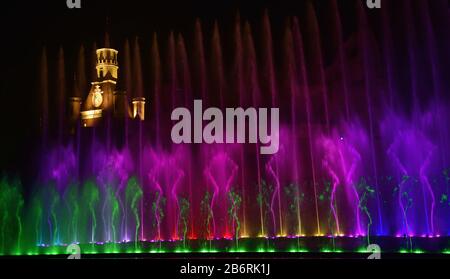 Schöne Brunnenschau. Große bunte dekorative Tanz-Wasserstrahl-LED-Lichtbrunnen zeigen nachts. Dunkler Hintergrund. Stockfoto