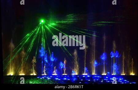 Bunte Wasserfontänen. Schöne Laser- und Brunnenschau. Große bunte dekorative Tanz-Wasserstrahl-LED-Lichtbrunnen zeigen nachts. Dunkel B. Stockfoto