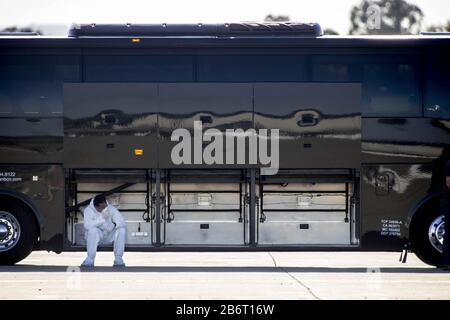 Oakland, Vereinigte Staaten. März 2020. Eine Transportarbeiterin macht eine Pause, nachdem sie Passagiere und ihr Gepäck am Mittwoch, den 11. März 2020, von einem Bus des Kreuzfahrtschiffs Grand Princess unterstützt hat, um ein gechartertes Flugzeug am Oakland International Airport in Oakland, Kalifornien zu starten. Foto von Peter DaSilva/UPI Credit: UPI/Alamy Live News Stockfoto